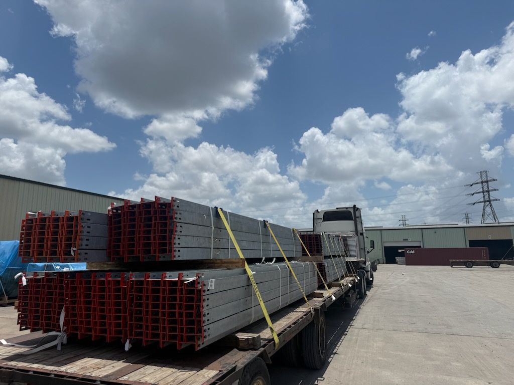 Galvanized steel beams strapped on a flatbed under a bright sky