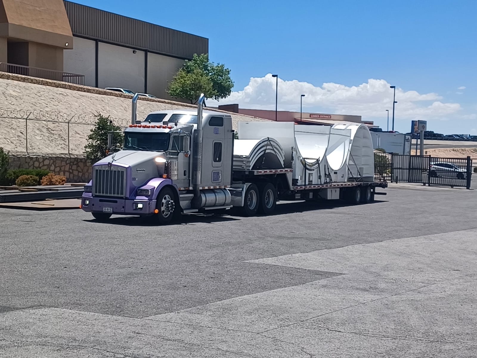 Cross-border freight delivery at a US-Mexico facility with active crane and flatbed operations