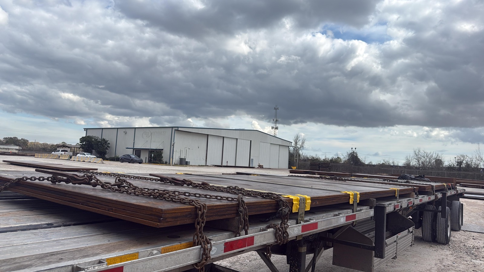 Steel plate chained and secured on a flatbed at a Houston yard