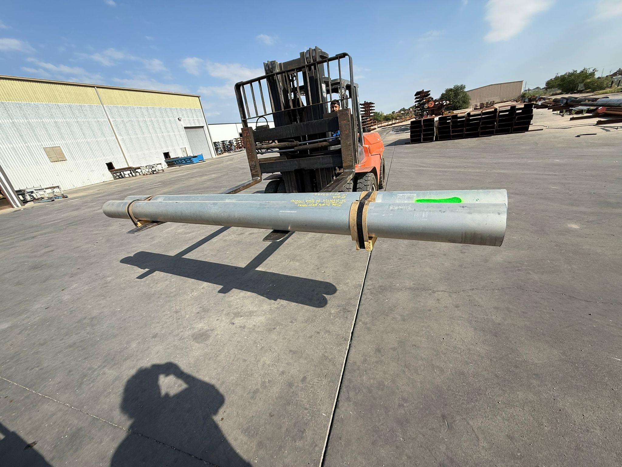 Worker securing pipe sections on a 40-foot hotshot flatbed for industrial project freight coordination