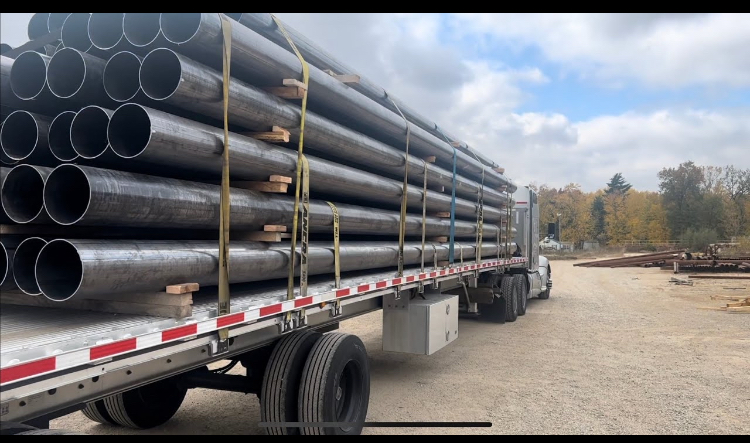 OCTG pipe bundles with color-coded end caps staged on a flatbed trailer at a Houston pipe yard